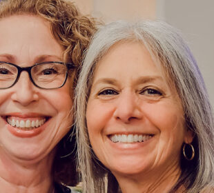Two smiling women attending Associated event