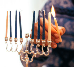 Man lighting candle on dreidel for Chanukah